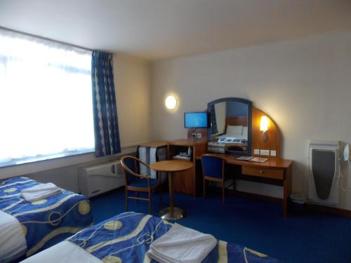 a hotel room with two beds and a desk and a mirror at London - Wembley International Hotel in London