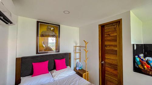 a bedroom with a bed with two pink pillows at Villa Lorenzo @ Caliraya Heights Resorts in Halang