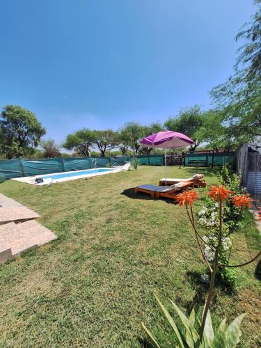 un jardín con una mesa y una sombrilla junto a una piscina en Cabañas Termas de Reyes en Termas de Río Hondo