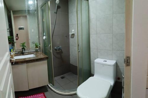 uma casa de banho com um chuveiro, um WC e um lavatório. em Monarch Parksuites - Balmoral Place (near NAIA, MOA, MOA Arena, DFA) em Manila