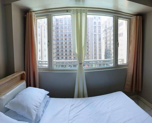 uma cama num quarto com uma janela com uma cidade em Monarch Parksuites - Balmoral Place (near NAIA, MOA, MOA Arena, DFA) em Manila