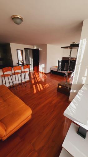 Oporto 83 في بوغوتا: غرفة معيشة مع أرضيات خشبية وكراسي برتقالية