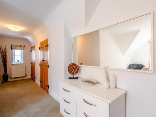 Cette chambre comprend une commode blanche et un miroir. dans l'établissement Hambury House, à West Lulworth