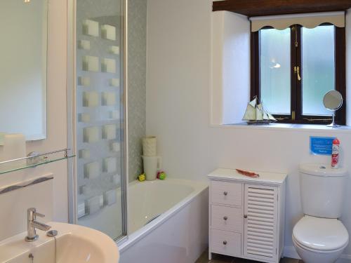a bathroom with a tub and a toilet and a sink at Little Content Farm Cottage in Cury