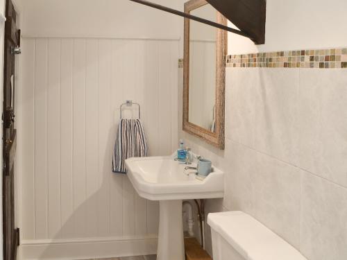 a bathroom with a sink and a mirror and a tub at Clutter Cottage in Widdrington