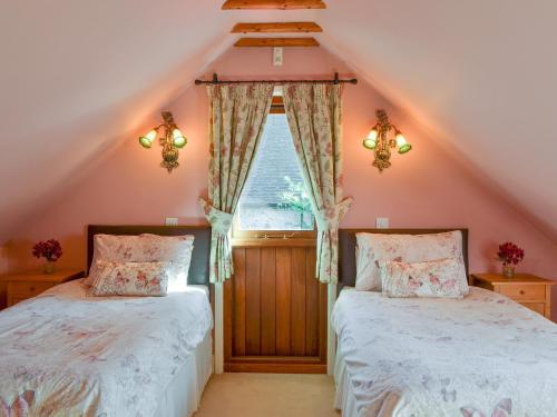 2 łóżka w sypialni na poddaszu z oknem w obiekcie Darwin Cottage - E4509 w mieście Jevington