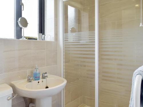 ein weißes Bad mit einem Waschbecken und einer Dusche in der Unterkunft Carols Cottage - E3043 in Blyford
