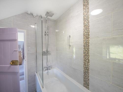 a bathroom with a bath tub and a shower at Blue Sails-jpv in Llangoed