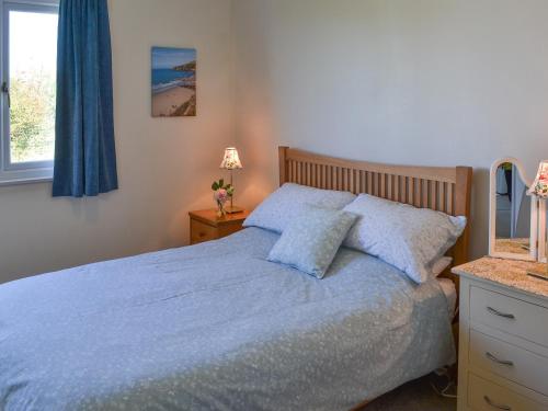 a bedroom with a bed with blue sheets and a window at Seafield in Llanrhyddlad