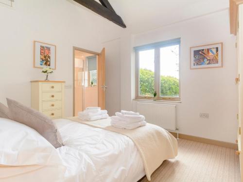 um quarto com uma cama branca e toalhas em Marigold em Shepton Mallet