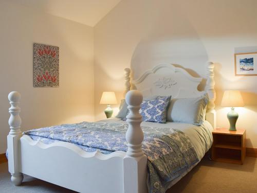 a bedroom with a white bed and two lamps at Lucklaw Steading Cottage in Logie