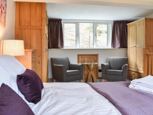 a bedroom with a bed and two chairs and a table at Hovera in Glenridding