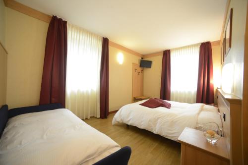 a hotel room with two beds and two windows at Hotel Vittoria in Folgaria