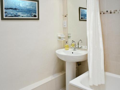 a white bathroom with a sink and a shower at The Stable in Crowan