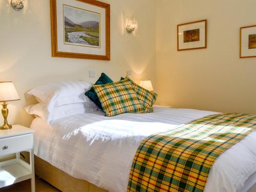 a bedroom with a white bed with a plaid blanket at The Old Inverchroskie Kennels in Enochdhu