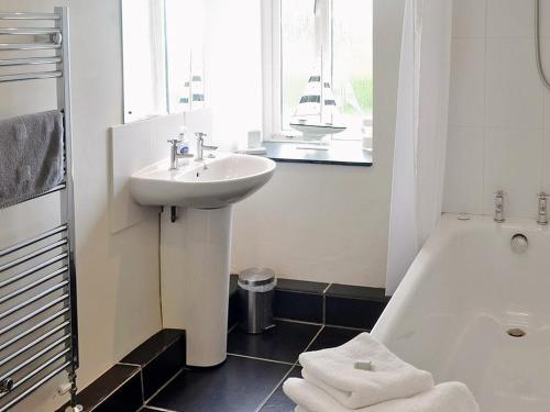 a white bathroom with a sink and a bath tub at Swallows Barn in Crowan