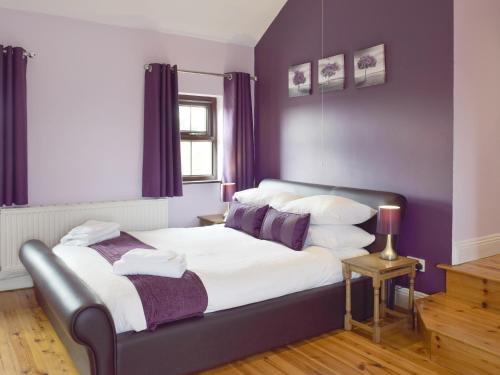 a bedroom with a bed with purple walls at Brynhowell in Llanglydwen