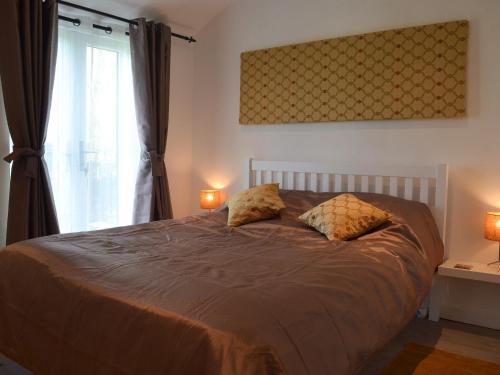 a bedroom with a bed with two pillows and a window at Lambs Cottage in Culmstock