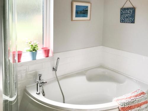 a white bath tub in a bathroom with a window at The Gallery in Mevagissey