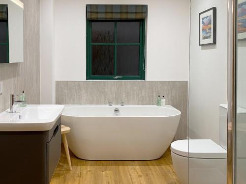 a bathroom with a large white tub and a toilet at Kyles View in Ollach