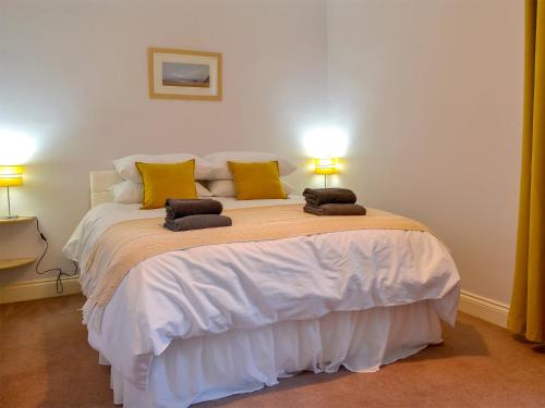 um quarto com uma grande cama branca com almofadas amarelas em Butterhole Cottage em Kelton