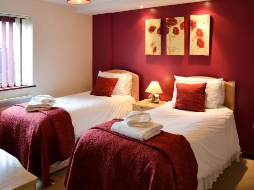 two beds in a room with red walls at Kestrel Cottage in Horning