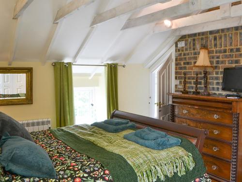 a bedroom with a large bed and a tv at Wisteria Cottage in Alnham
