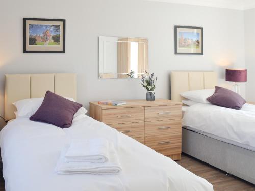 a bedroom with two beds and a wooden dresser at Smithfield House in Tarbolton