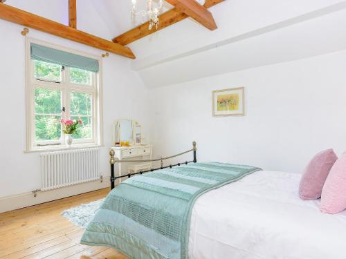 a white bedroom with a bed and a window at Station House in Millers Dale