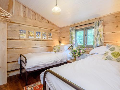 two beds in a room with wooden walls at Kingfisher Cabin in Croft