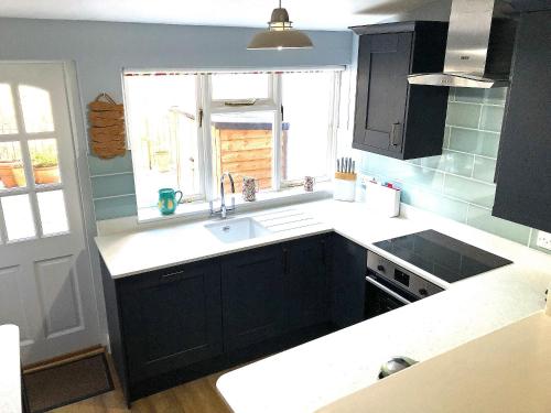 a kitchen with black cabinets and a sink and a window at Felicity House in Staithes