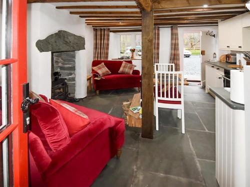 a living room with a red couch and a fireplace at Field House Cottage - Uk12573 in Borrowdale