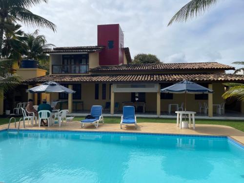 uma piscina em frente a uma casa com cadeiras e guarda-sóis em Casa Resort em Cacha-Prego