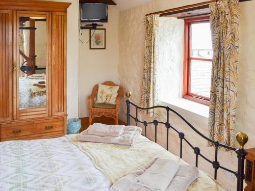 a bedroom with a bed and a mirror and a chair at Cowslip - Uk12060 in Lower Boscaswell