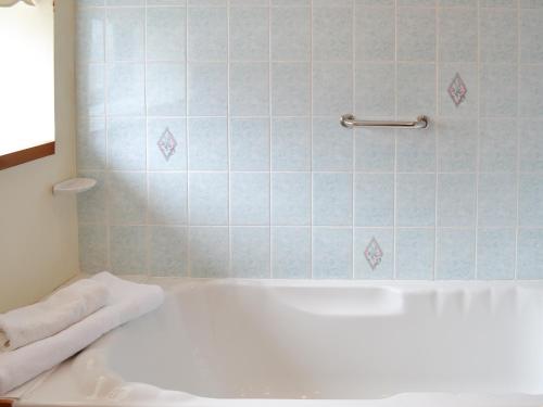 a white bath tub in a bathroom with blue tiles at Cowslip - Uk12060 in Lower Boscaswell