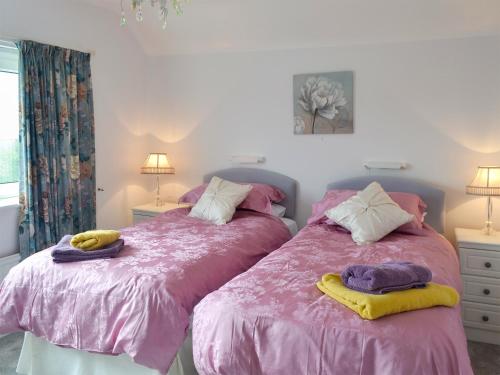 Duas camas num quarto com lençóis e toalhas cor-de-rosa em Swn-y-wylan em Criccieth