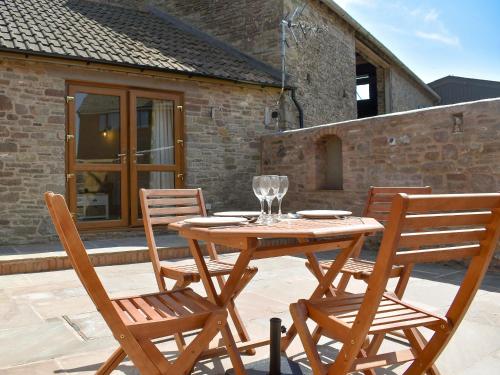 uma mesa de madeira e cadeiras num pátio em Lambing Shed - Uk12380 em Lydney