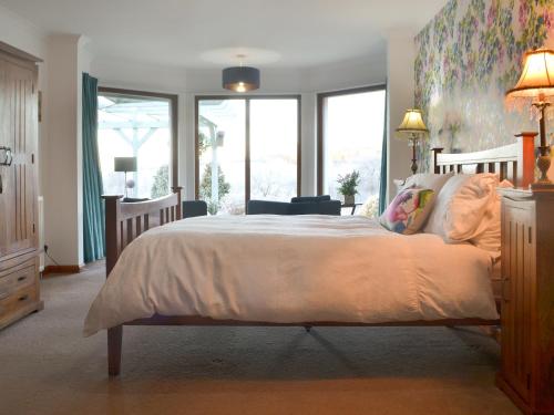 a bedroom with a large bed with a large window at Cushendall House in Torcastle