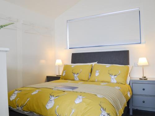 a bedroom with a bed with a yellow comforter at The Isle View Nest - Uk13547 in Broadford