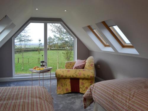 - une chambre avec une chaise et une grande fenêtre dans l'établissement Torcross Barn, à Tarbolton