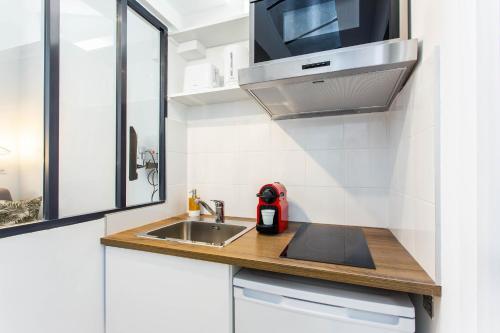 a small kitchen with a sink and a microwave at Great studio - Le MaraisRépublique in Paris