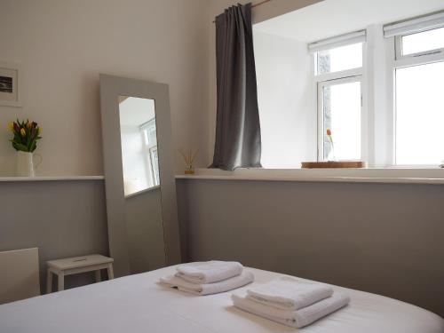 2 toallas sentadas en una cama en una habitación con ventana en Apartment 6 harlech en Criccieth