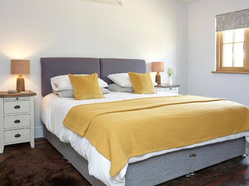 um quarto com uma cama grande e um cobertor amarelo em The Barn em Brighstone