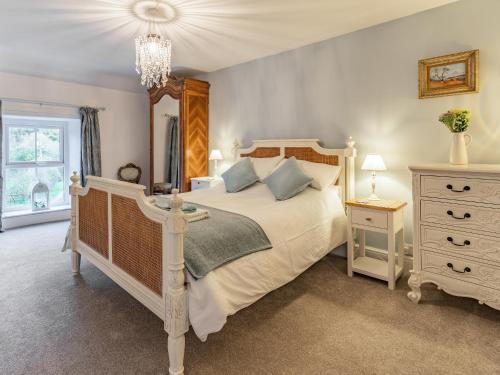 a bedroom with a large bed and a chandelier at Pwll Farmhouse in Llanllawdog