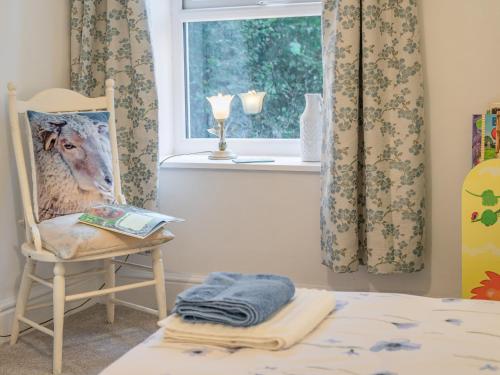 a bedroom with a bed and a chair and a window at Pwll Farmhouse in Llanllawdog