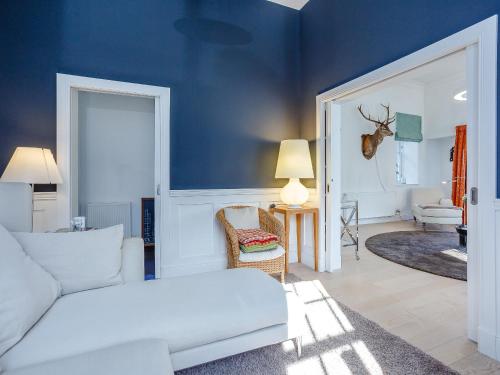 a living room with a white couch and a blue wall at Skene House Court in Dunecht