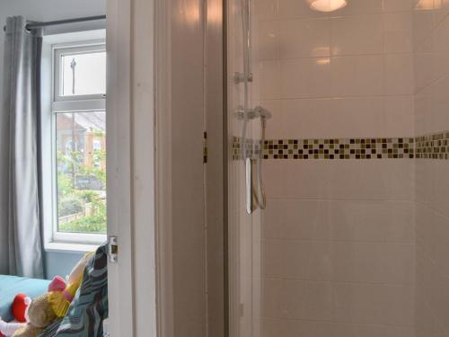 a bathroom with a shower with a glass door at Cushty Cottage in Winterton-on-Sea