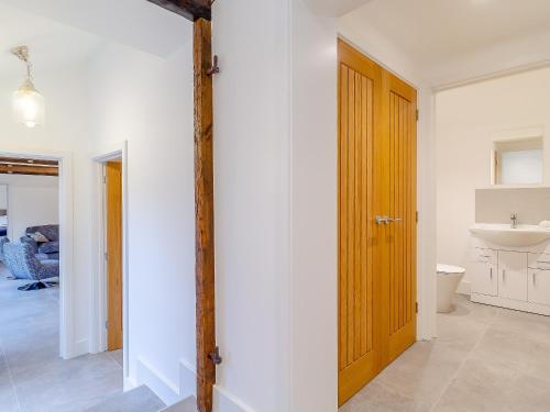 a bathroom with a wooden door and a sink at Skylark Barn-uk31354 in Swaffham