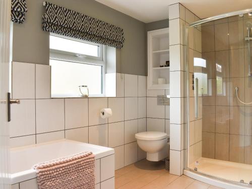 uma casa de banho com uma banheira, um WC e um chuveiro em The Cottage At Stainsacre Hall em Hawsker