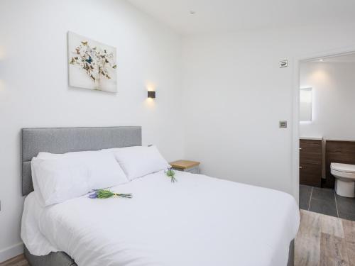 a bedroom with a white bed and a bathroom at Marshall Cottage in Santon